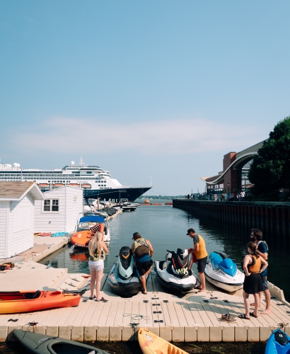 People enjoying water sports such as kayaking, paddleboarding, and boating in Charlottetown Harbour on a sunny summer day.