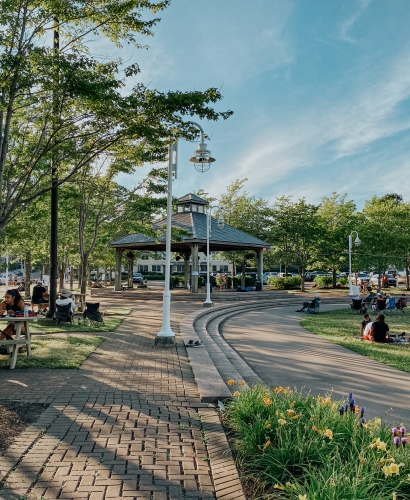 People relaxing and sitting throughout Confederation Landing Park in Charlottetown, Prince Edward Island, near the waterfront on a summer day.