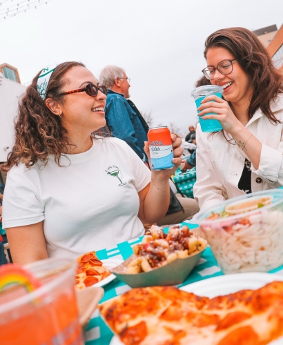Friends eating and drinking together at a Charlottetown PEI street festival with local food vendors