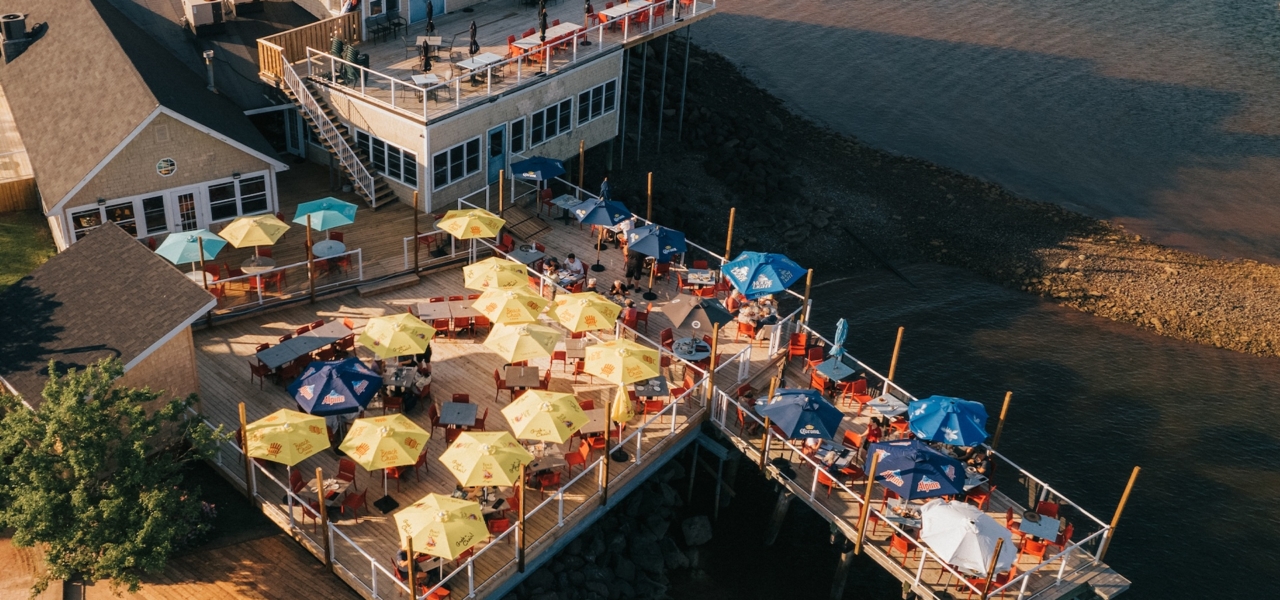 Guests dining on the waterfront patio at Lobster on the Wharf in Charlottetown, Prince Edward Island, overlooking the harbour and boats.
