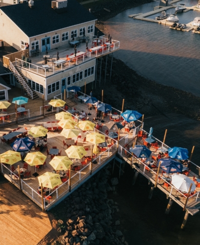 Guests dining on the waterfront patio at Lobster on the Wharf in Charlottetown, Prince Edward Island, overlooking the harbour and boats.