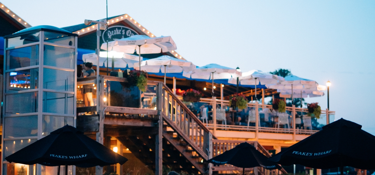 Guests dining on the outdoor waterfront patio at Peake’s Quay Restaurant in Charlottetown, Prince Edward Island, overlooking the harbour.