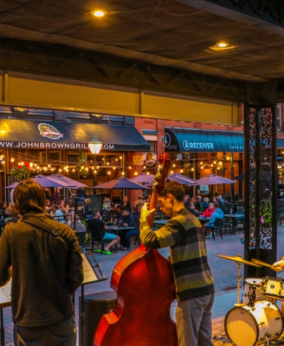 Musicians performing live on Victoria Row pedestrian street in downtown Charlottetown with people enjoying outdoor seating and patios.