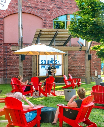 Live musicians performing on the outdoor patio at Founders Food Hall & Market in Charlottetown, Prince Edward Island, with guests enjoying food and drinks.