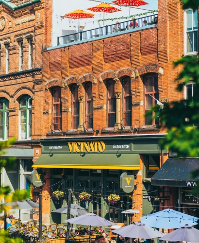 People walking and dining along Victoria Row pedestrian street in downtown Charlottetown, Prince Edward Island, with outdoor patios and historic buildings.