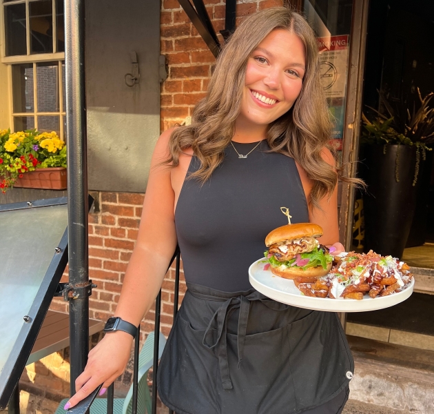 Server delivering food and drinks at Brickhouse Kitchen & Bar's outdoor patio in downtown Charlottetown, Prince Edward Island.