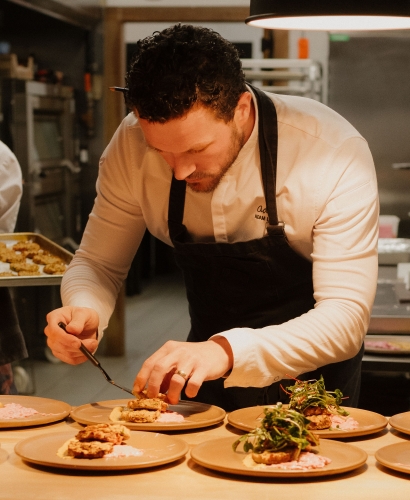 A chef preparing and plating food during a hands-on cooking class at Ada Culinary Studio in Charlottetown, Prince Edward Island.