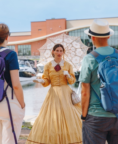An actor in period costume leads a heritage walking tour through downtown Charlottetown, Prince Edward Island, sharing stories of the city's past.