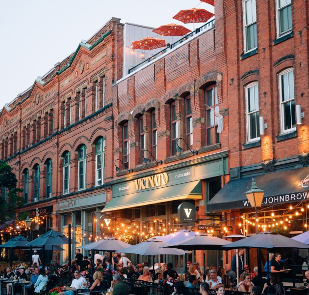 Outdoor patios along Victoria Row in downtown Charlottetown, Prince Edward Island, with restaurants, seating, and a vibrant street scene.