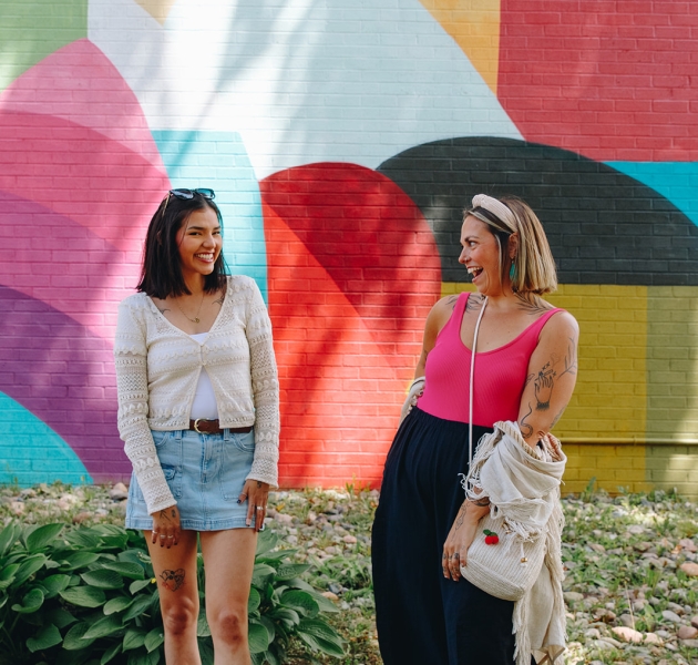 Girls standing in front of a colourful mural on the side of a building in downtown Charlottetown, Prince Edward Island.