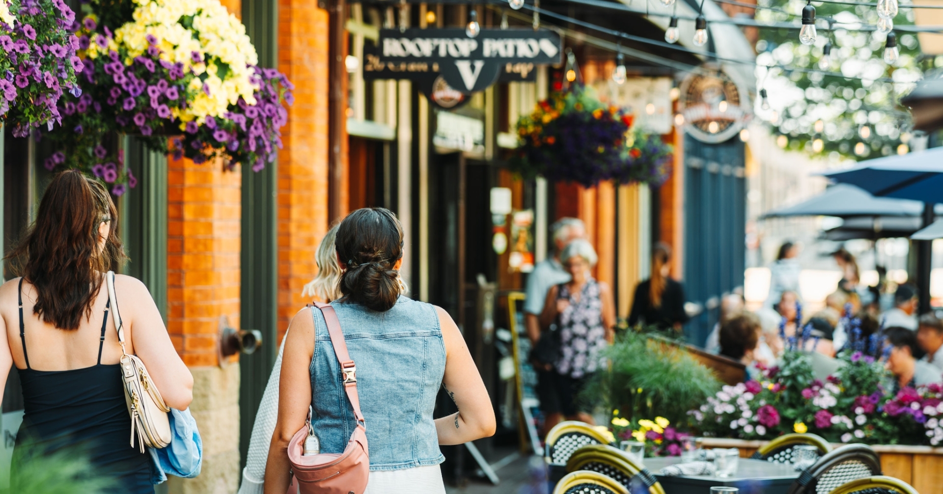 Girls walking along Victoria Row in downtown Charlottetown, Prince Edward Island, surrounded by restaurants, patios, and historic streetscape.